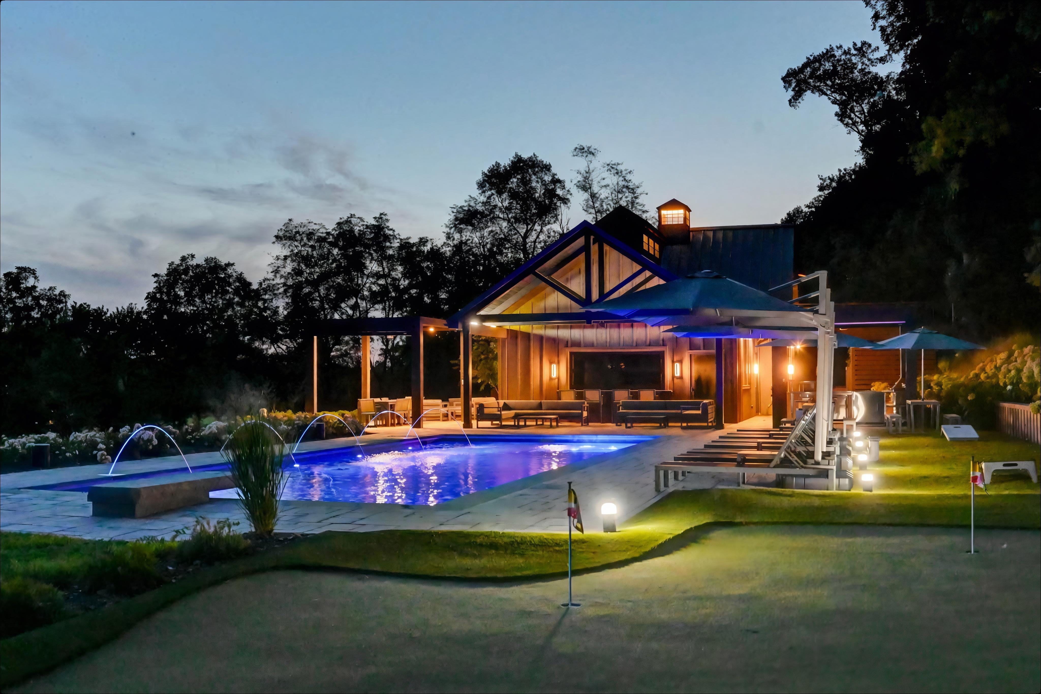 Custom-built post frame residence with pool and outdoor living space at dusk